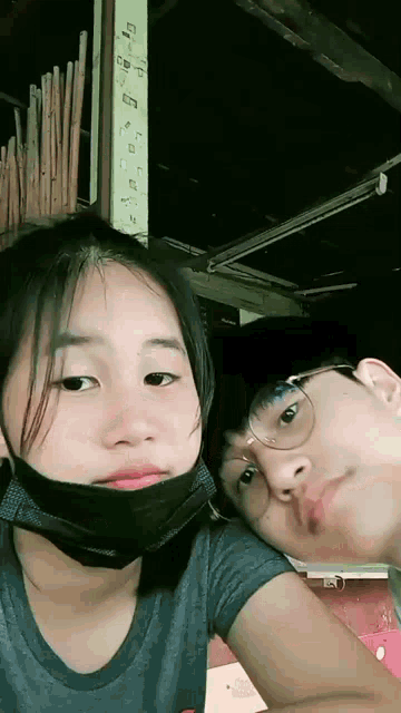 a girl wearing a mask and a boy wearing glasses are posing for a picture