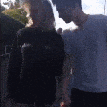 a man and a woman are standing next to each other holding hands