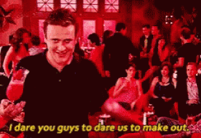 a man in a black shirt is standing in front of a crowd and says " i dare you guys to dare us to make out