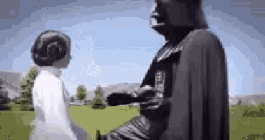 a man dressed as darth vader is standing next to a woman dressed as princess leia .