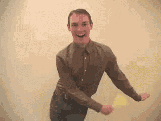 a man in a brown shirt and jeans is dancing in a room .