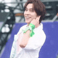 a man wearing a white shirt and a green scarf around his neck is smiling .
