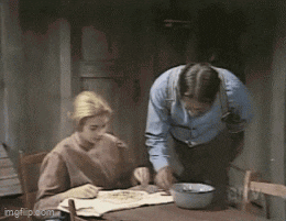a man and a woman are sitting at a table with a bowl of food in front of them
