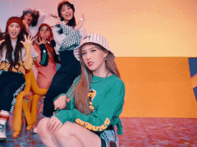 a girl in a green sweater is kneeling down in front of a group of girls wearing hats .