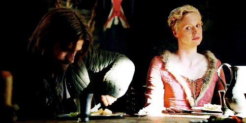 a man and a woman are sitting at a table with a flag in the background
