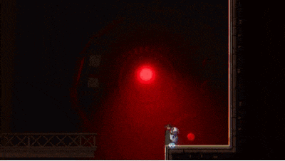 a person is standing in a dark room with a red light coming out of it .