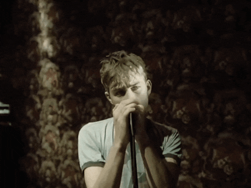 a young man singing into a microphone with the words woo-hoo written below him