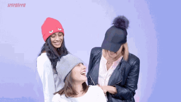 three women wearing beanies and hats are laughing with the words seventeen in the corner