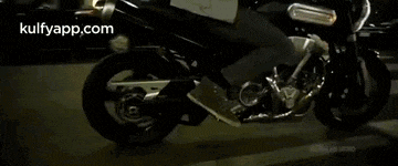 a motorcycle is driving down a city street at night and the website kulfyapp.com is displayed in the corner