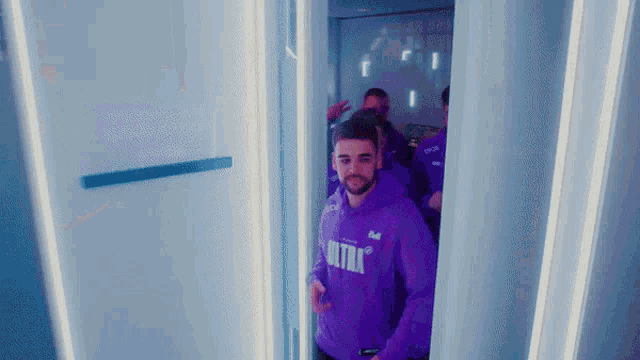 a man in a purple ultra hoodie is walking through a doorway