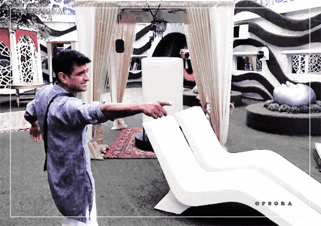a man is pointing at a white chair with the word opsora on the bottom