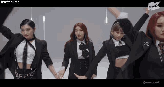 a group of women in suits are dancing in front of a sign that says thek