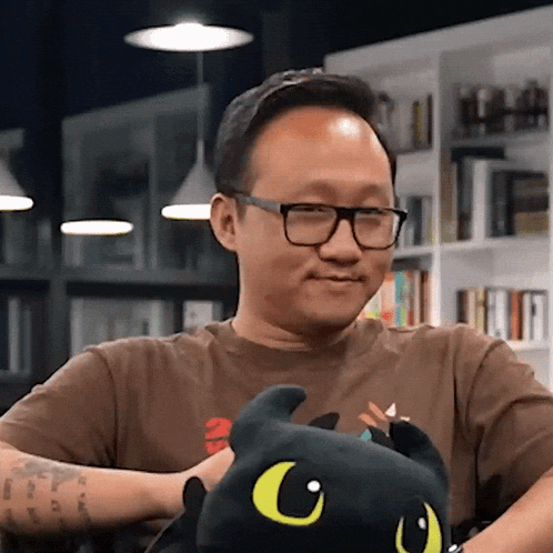 a man wearing glasses is holding a stuffed animal with the letter c on its face