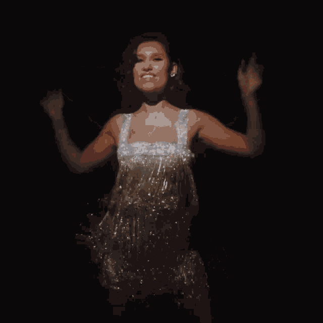 a woman in a sparkly dress is dancing on a stage .