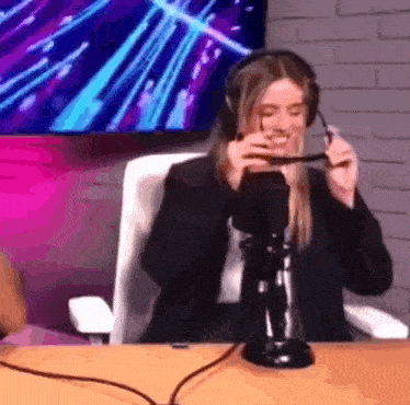 a woman wearing headphones is sitting in front of a microphone and smoking a cigarette .