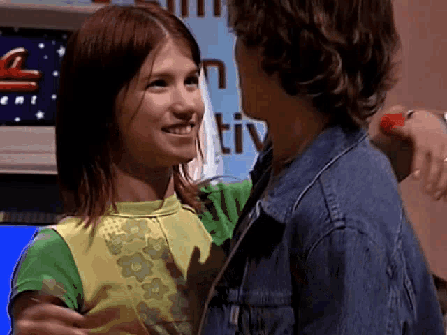 a boy and a girl are hugging each other in front of a tv screen