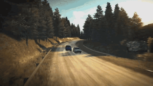 three cars are driving down a dirt road with trees on the side