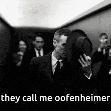 a man in a suit and tie holds his hat over his face with the words they call me oofenheimer below him