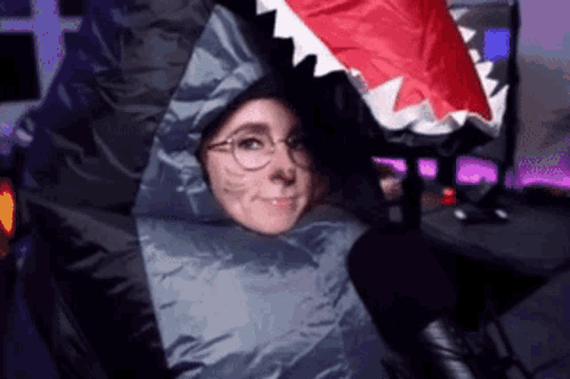 a woman wearing a shark costume is sitting in a chair .