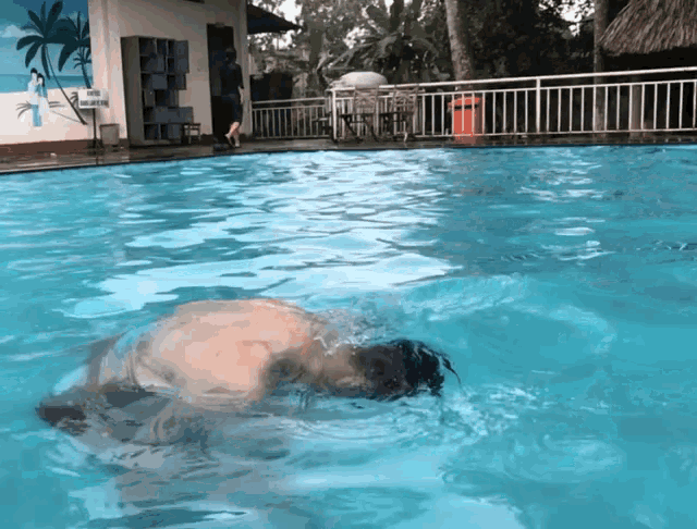 a man is swimming in a pool with palm trees painted on the wall behind him