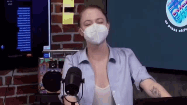 a woman wearing a mask is talking into a microphone .