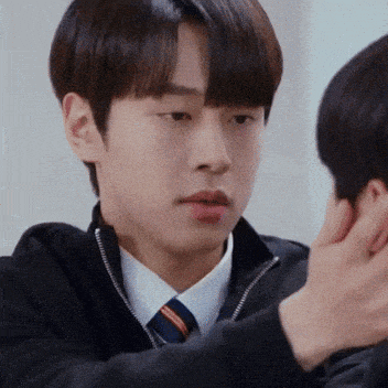 a man in a suit and tie is being touched by another man 's hand .