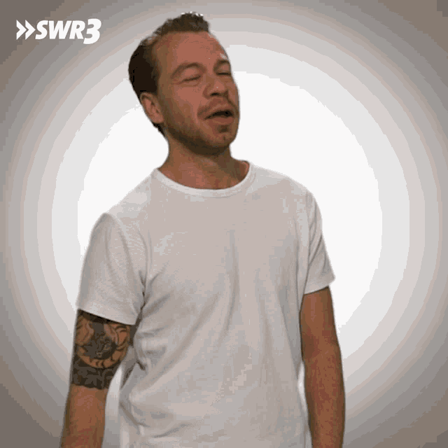 a man with a tattoo on his arm is wearing a white shirt with the letters swr3 on it