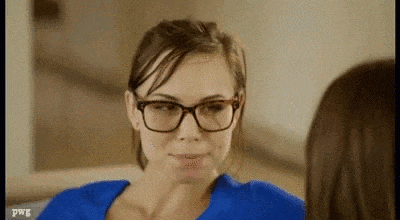 a woman wearing glasses and a blue shirt is sitting on a couch talking to another woman .