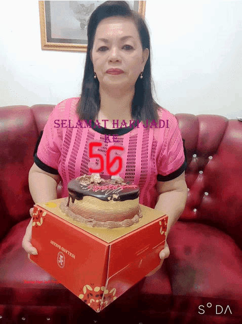 a woman in a pink shirt is holding a cake that has the number 50 on it