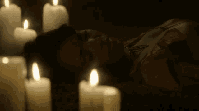 a woman laying on the floor with candles around her