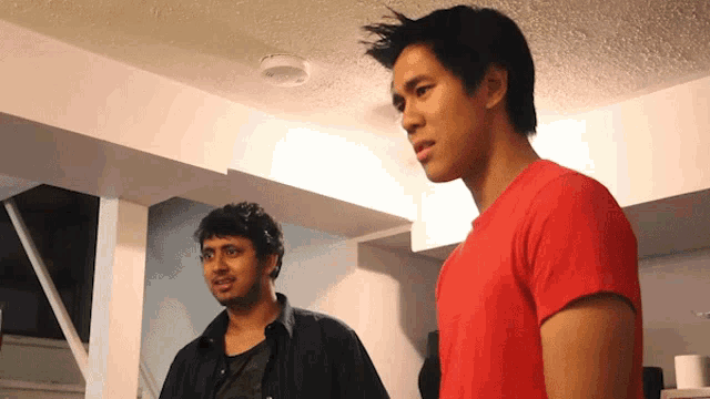 a man in a red shirt is standing next to another man in a black shirt
