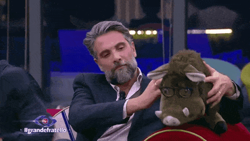 a man with a beard is holding a stuffed animal with glasses