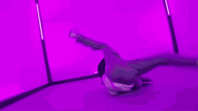 a person is doing a handstand in front of a purple wall