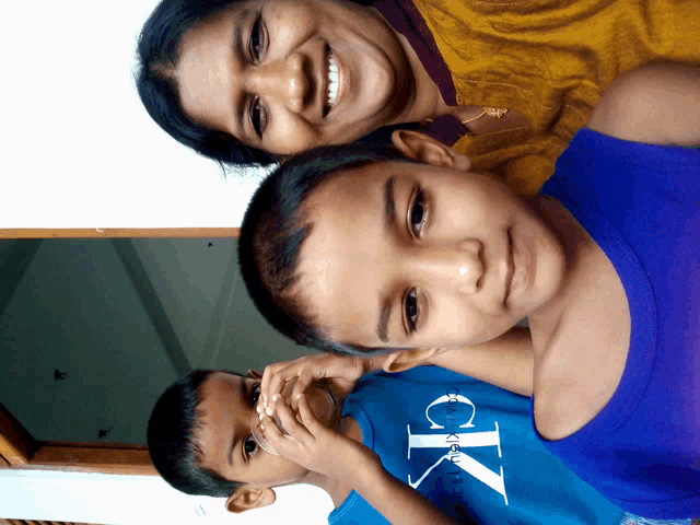 a boy wearing a blue calvin klein shirt smiles with his mother