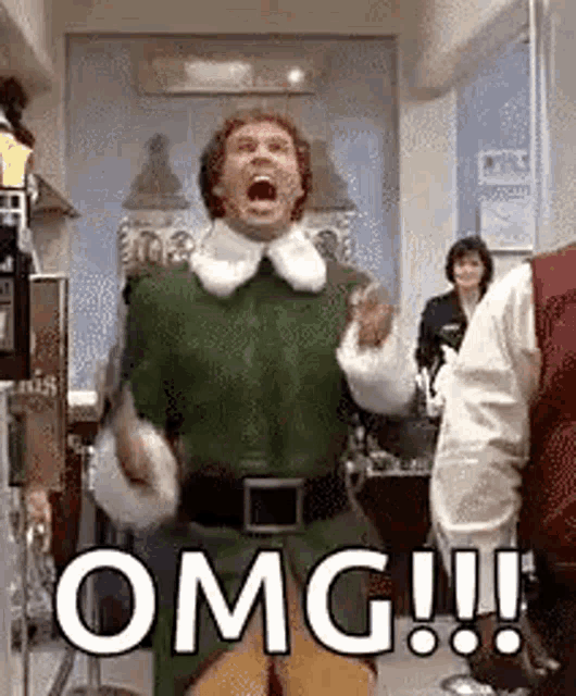 a man in a green elf costume is standing in a room with his mouth open and screaming .