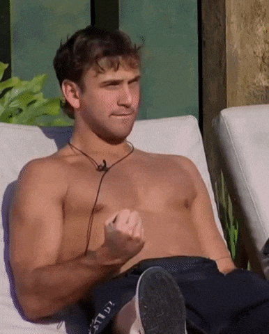 a shirtless man is sitting on a couch wearing headphones and making a funny face .