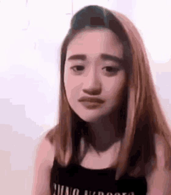 a young woman with long hair is making a funny face while wearing a black tank top .