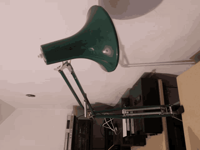 a green lamp is sitting on top of a wooden desk