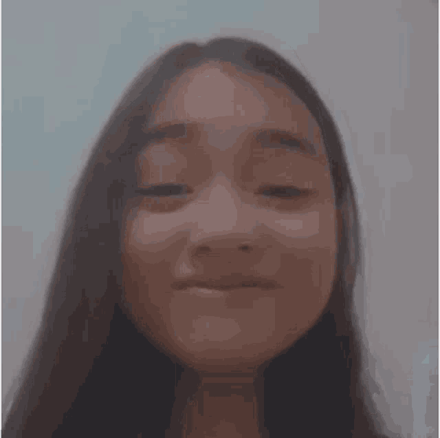 a girl with long hair is making a funny face with her hands .