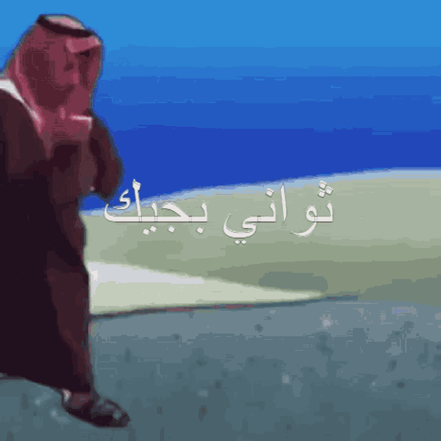 a man in a turban is walking on a road with arabic writing on it