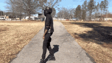 a man in a black hoodie is walking down a path in a park