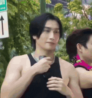 a man in a black tank top is holding a microphone while standing in front of a sign that has an arrow pointing up