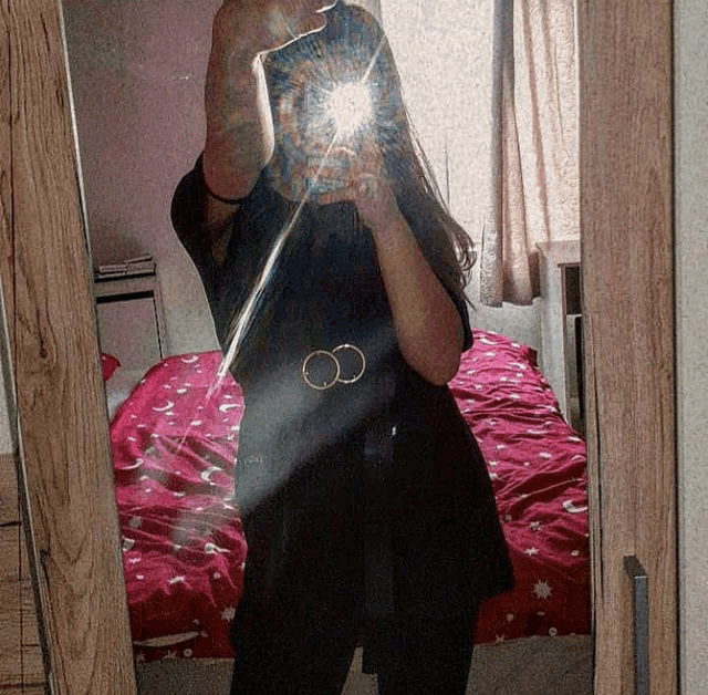 a woman taking a picture of herself in a mirror with the letter c on her shirt