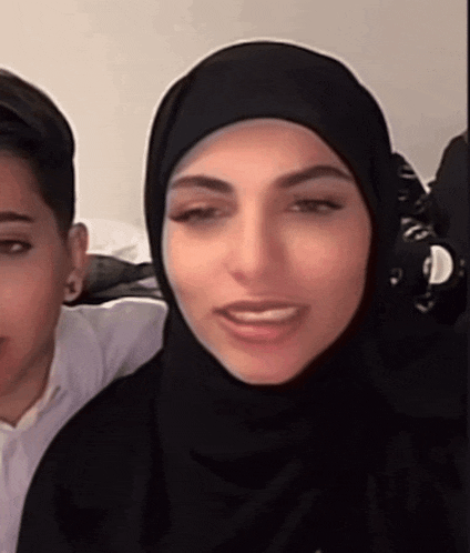a woman wearing a black hijab is smiling and looking at the camera .