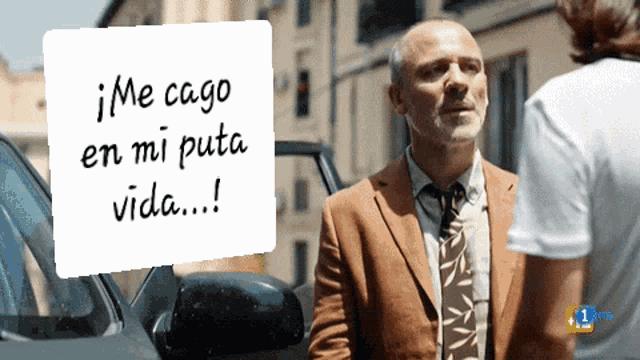 a man in a suit and tie is standing next to a car with a sign that says me cago en mi puta vida