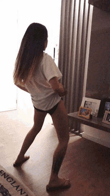 a woman dancing in a living room with a rug that says england on it