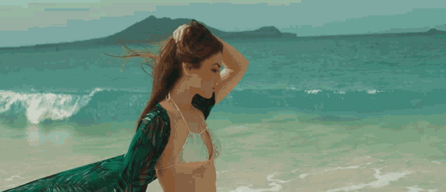 a woman in a bikini stands on the beach