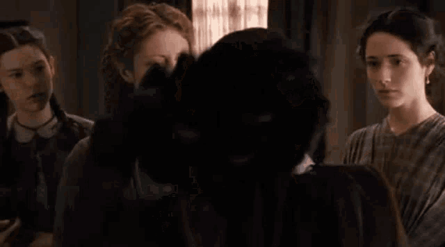 a group of women are standing next to each other in a room talking to each other .