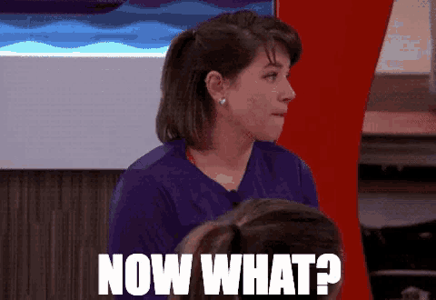 a woman in a purple shirt with the words now what on her face