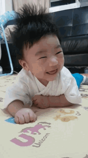 a baby is laying on a unicorn mat and smiling